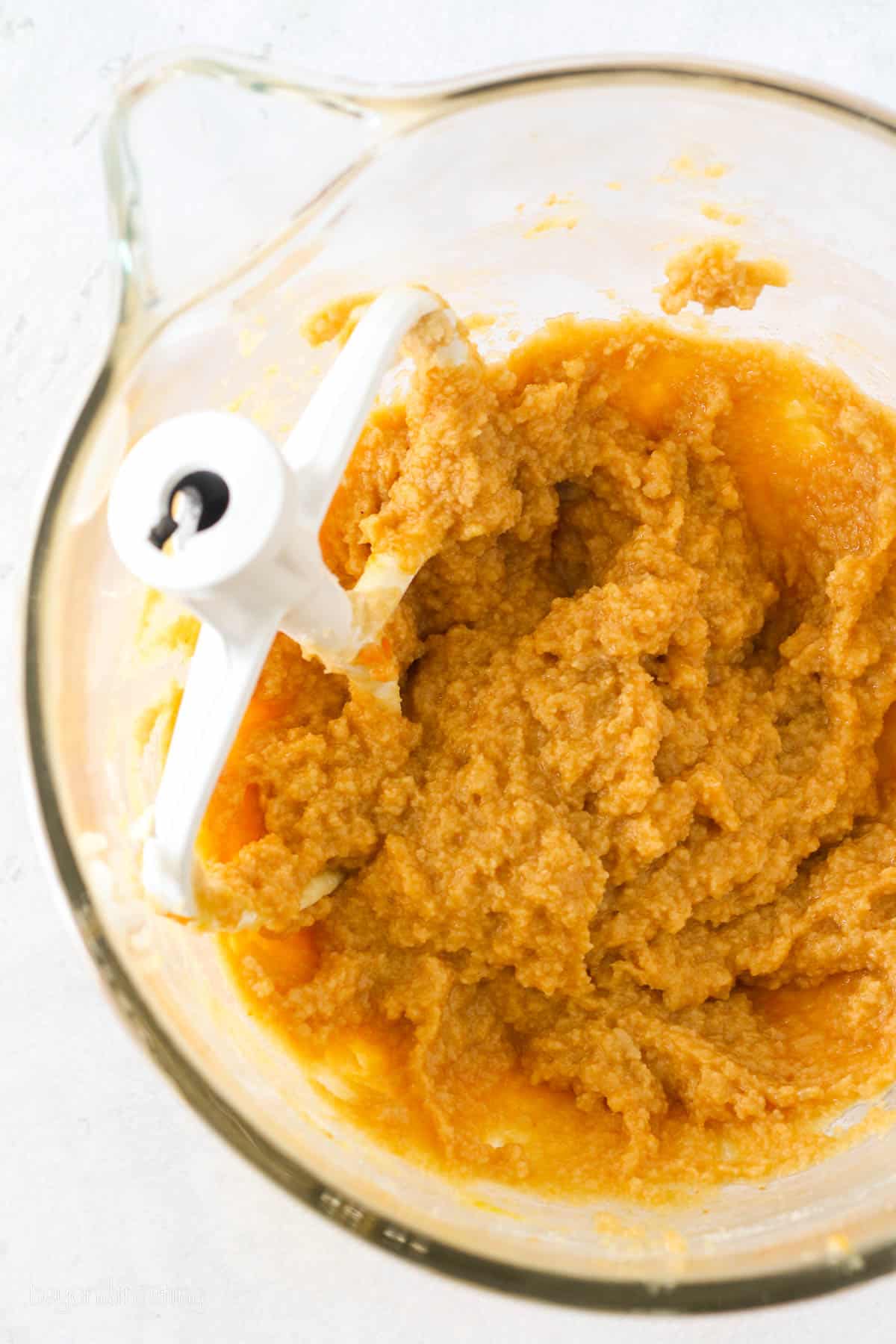Pumpkin puree combined in a mixing bowl with cookie dough ingredients.