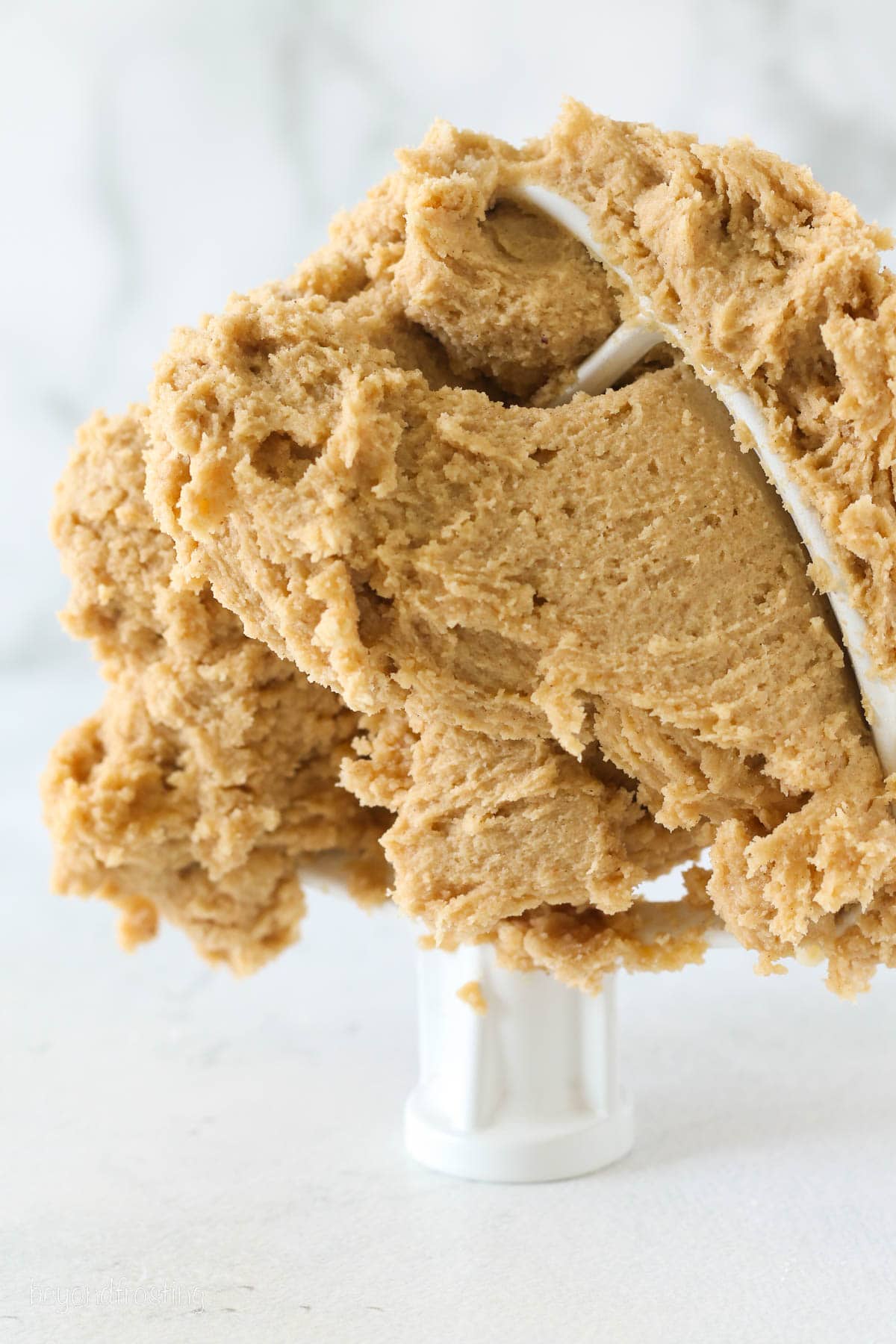 Pumpkin sugar cookie dough stuck to a stand mixer attachment.