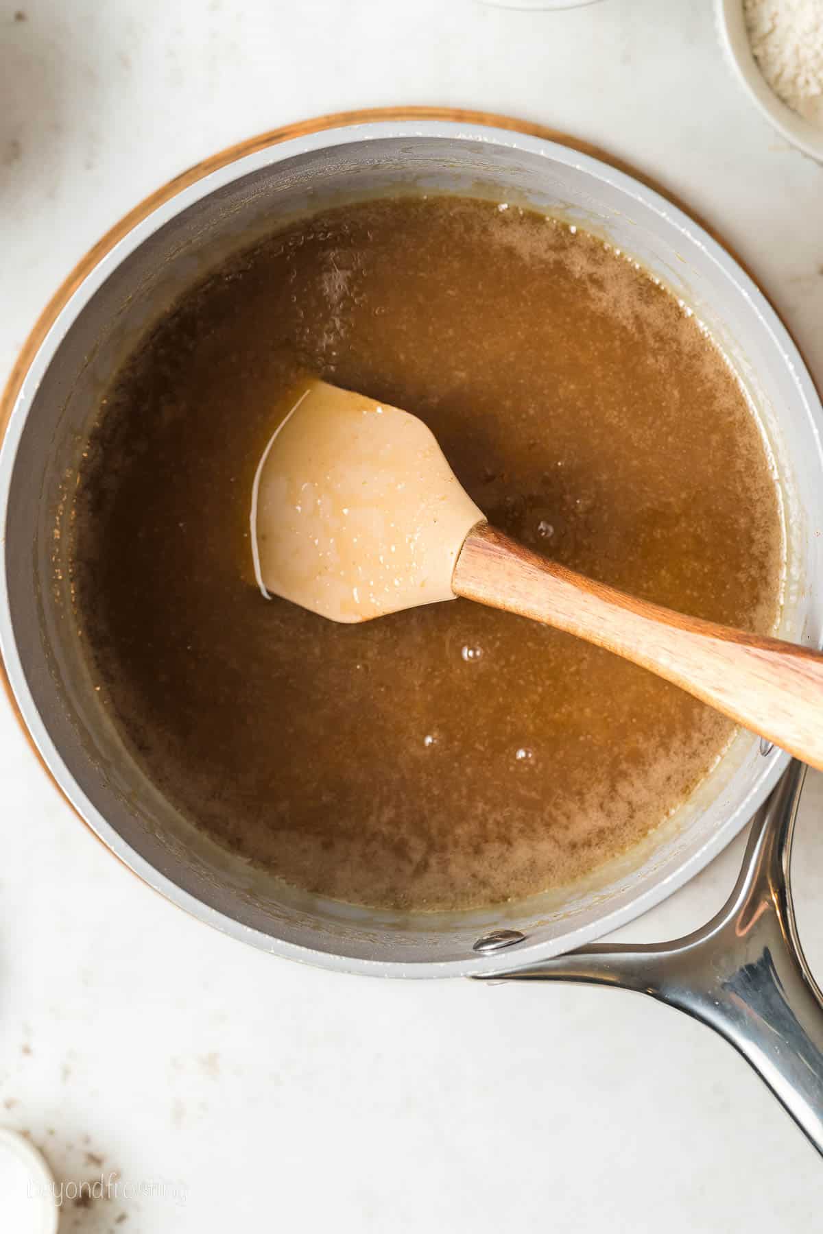 A pot of homemade caramel sauce with a spatula