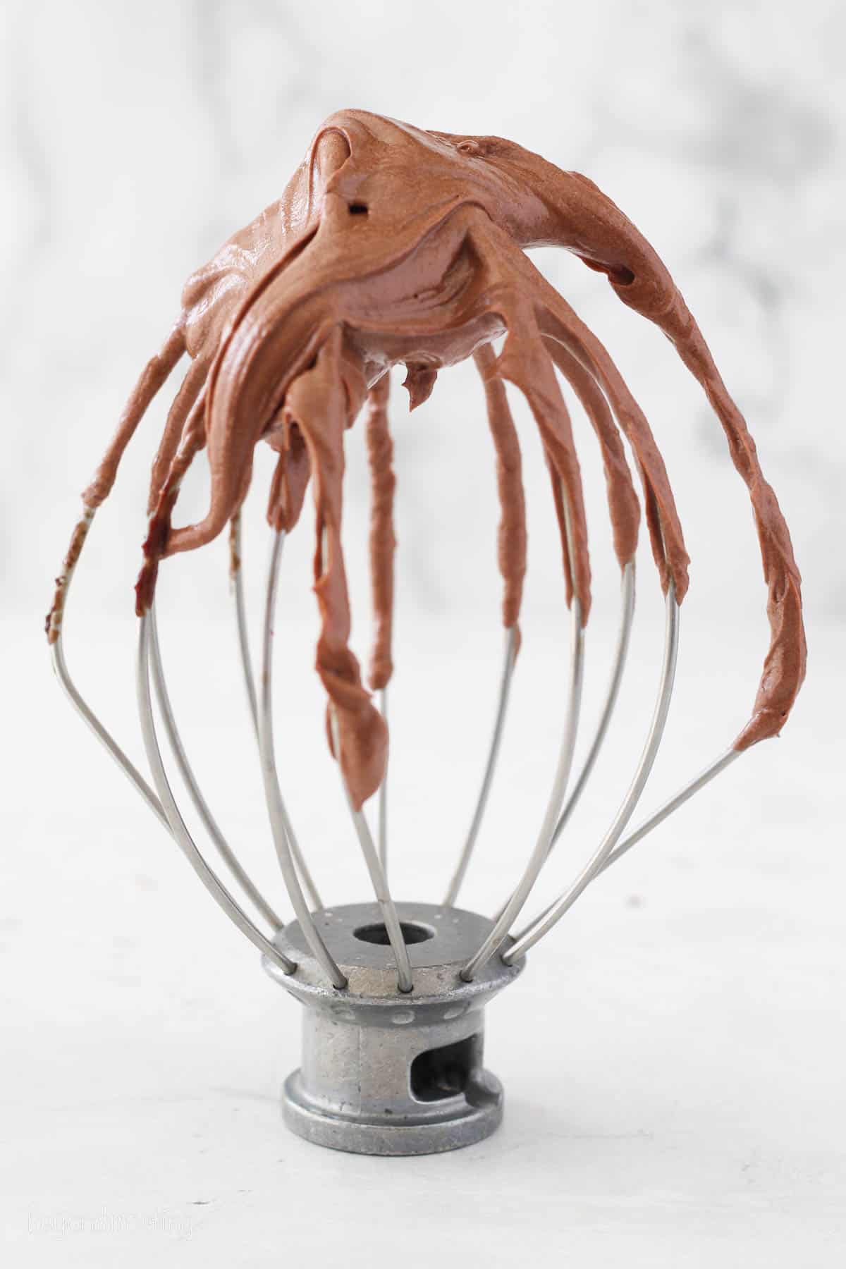 A stand mixer attachment topped with whipped ganache frosting.
