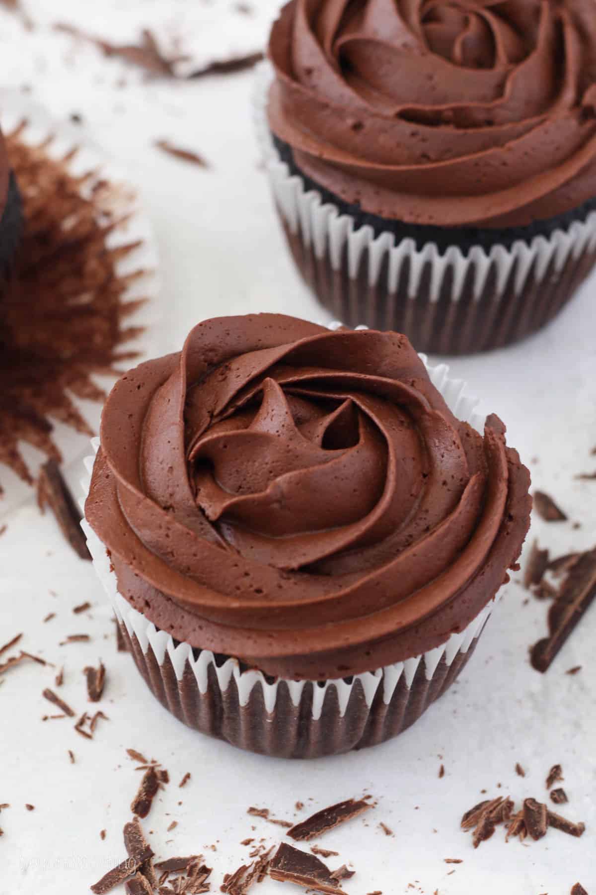 Two chocolate cupcakes topped with swirls of whipped ganache frosting.