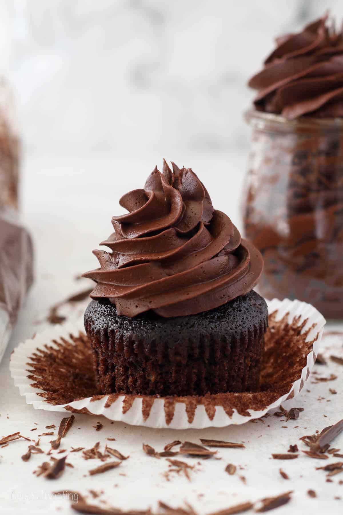 An unwrapped chocolate cupcake topped with a swirl of whipped ganache frosting.