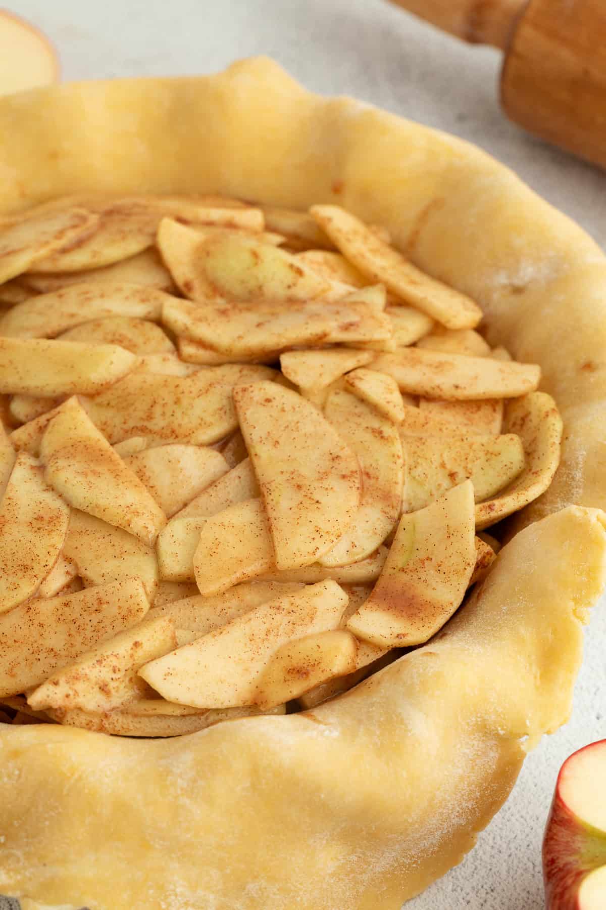 A prepared flaky pie crust filled with homemade apple pie filling in a pie dish.