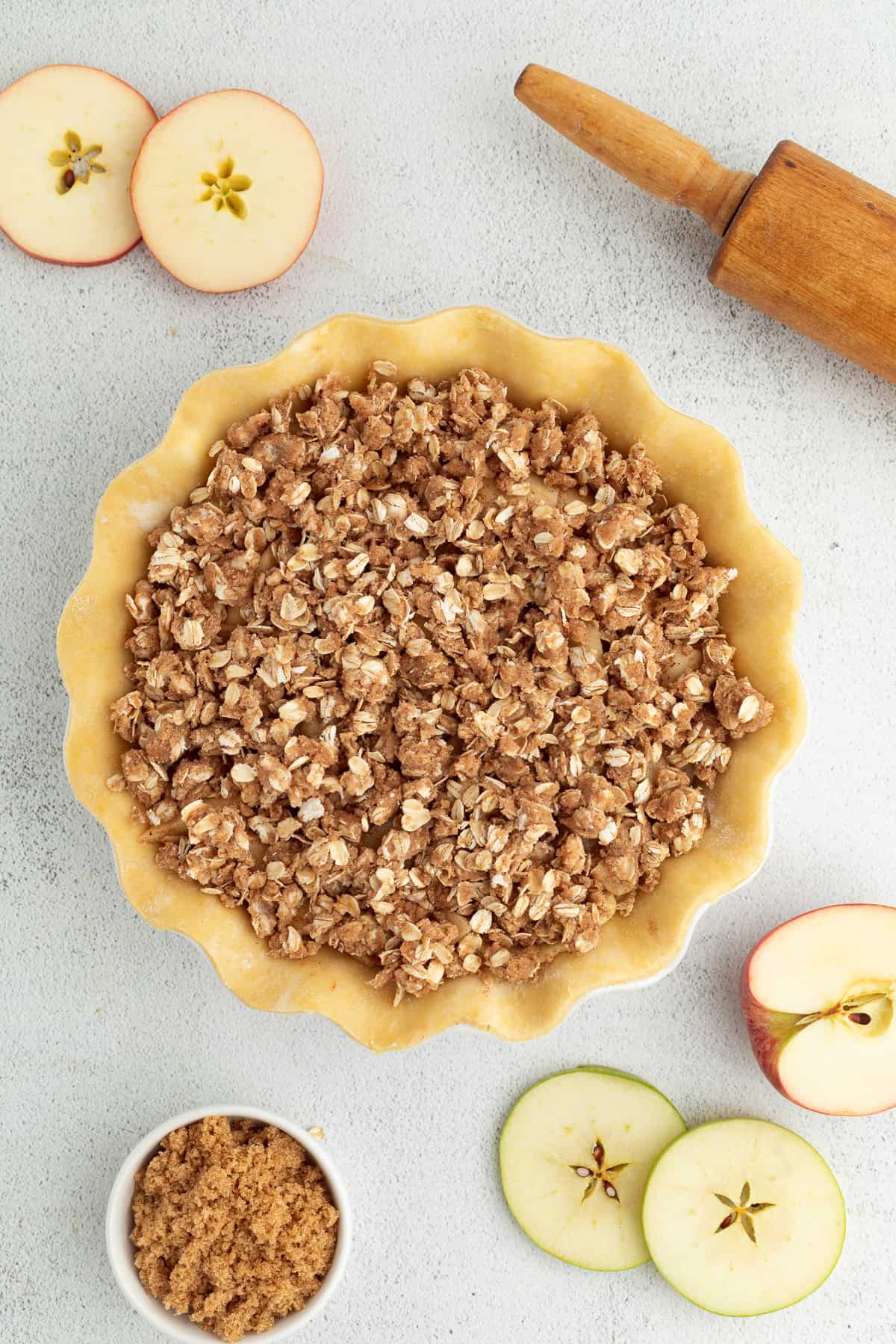 Overhead view of an unbaked apple pie topped with oat crumble.