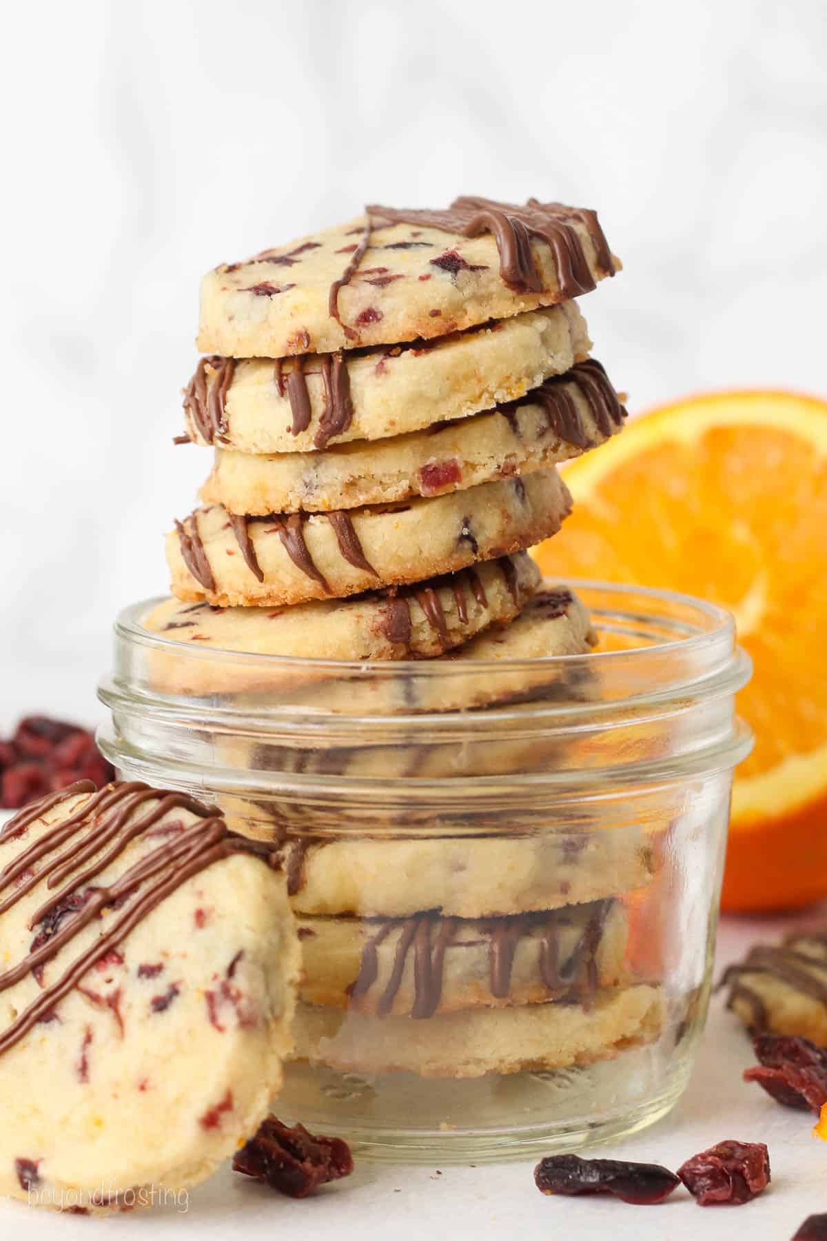 A stack of cranberry orange shortbread cookies in a glass dish.