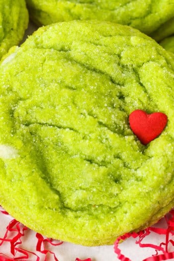 Close up of a grinch cookie garnished with a red heart sprinkle.