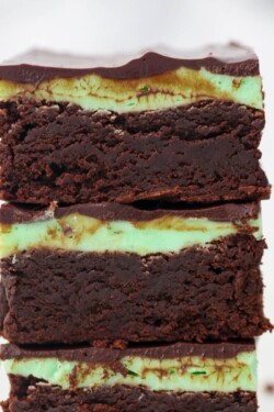 A stack of brownies frosted with mint buttercream and a ganache topping