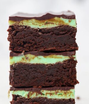 A stack of brownies frosted with mint buttercream and a ganache topping