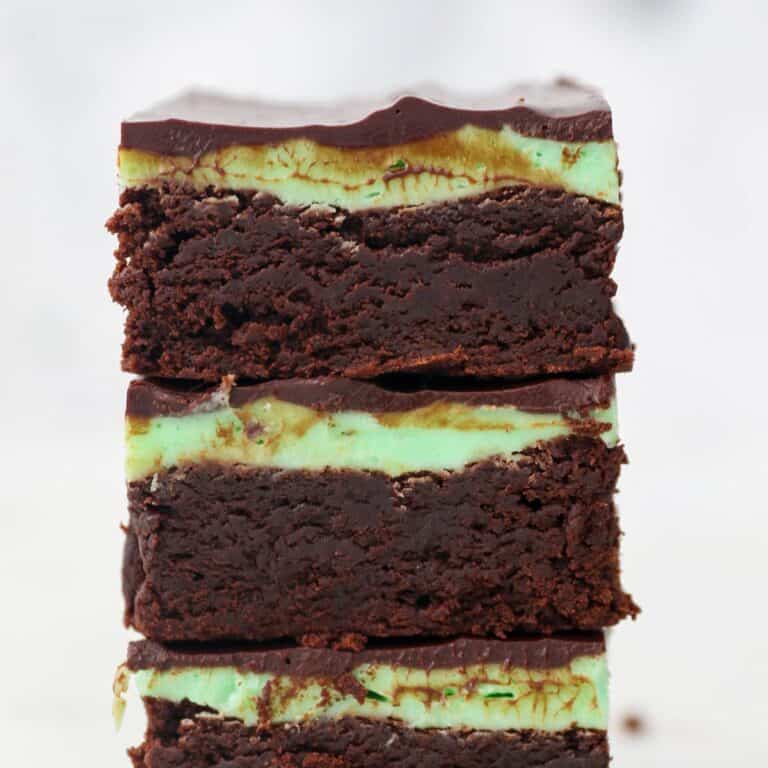 A stack of brownies frosted with mint buttercream and a ganache topping