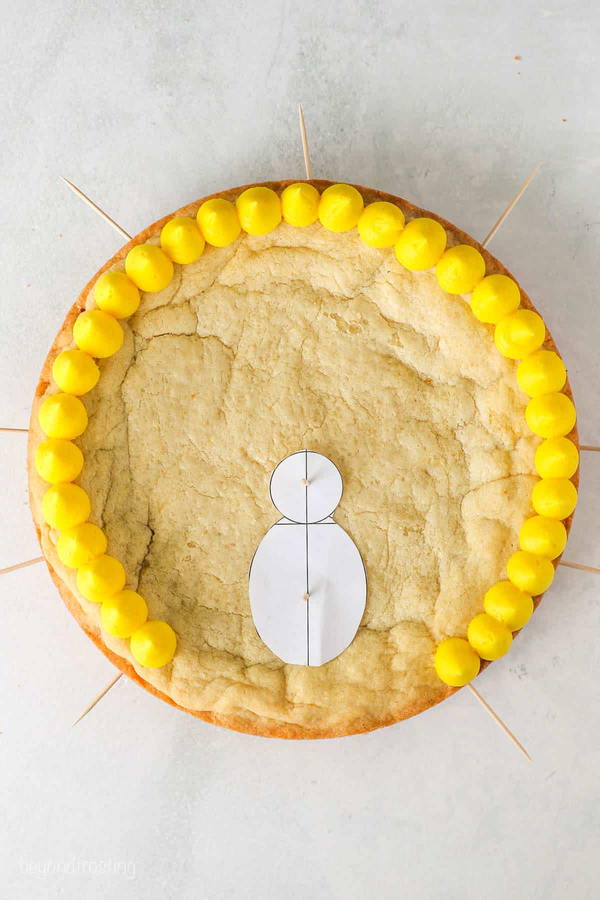 Overhead view of a cookie cake with a row of yellow frosting on the outside