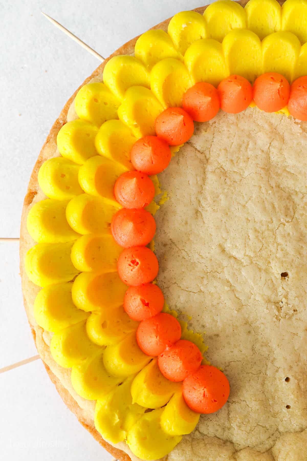 Overhead shot of orange and yellow buttercream frosting on a cookie cake demonstrating the pedal frosting technique