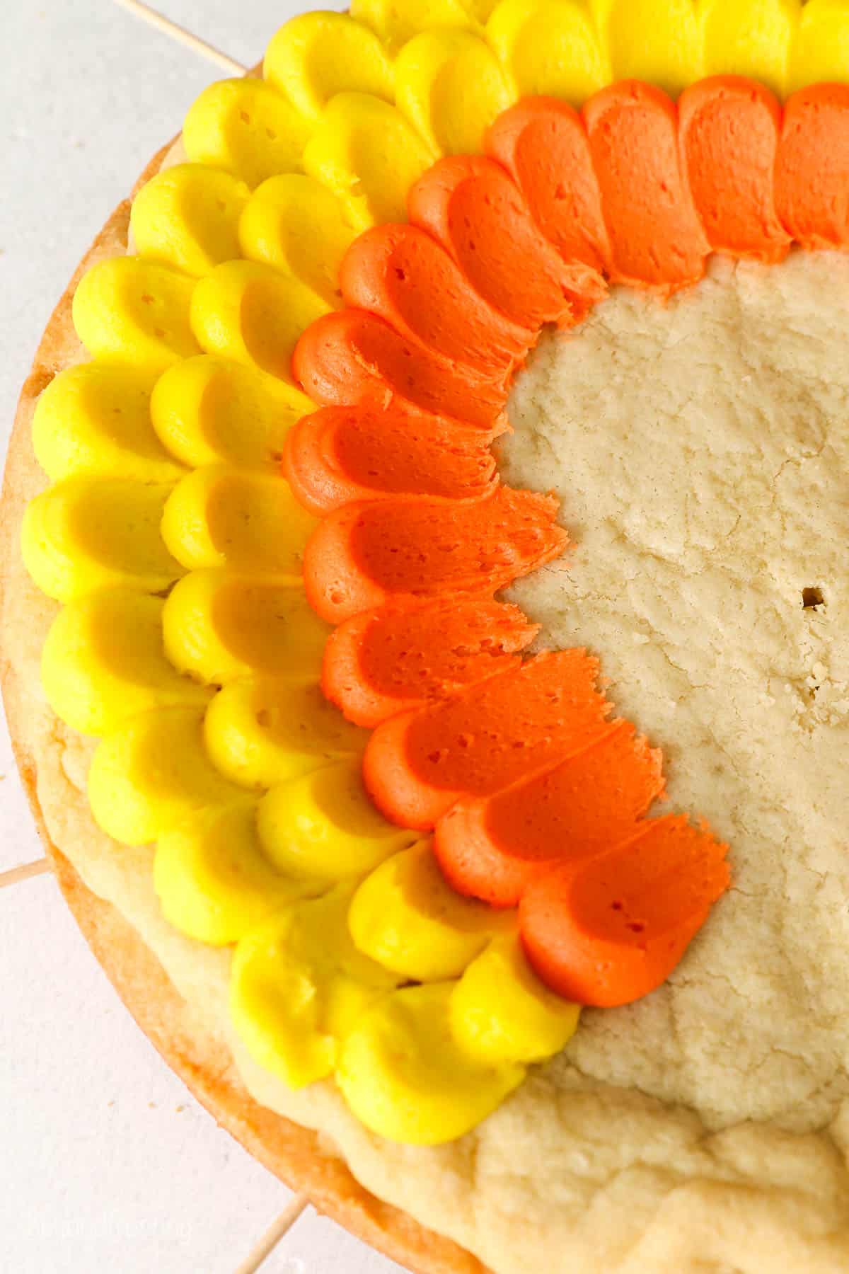 close up of orange and yellow buttercream frosting on a cookie cake demonstrating the pedal frosting technique