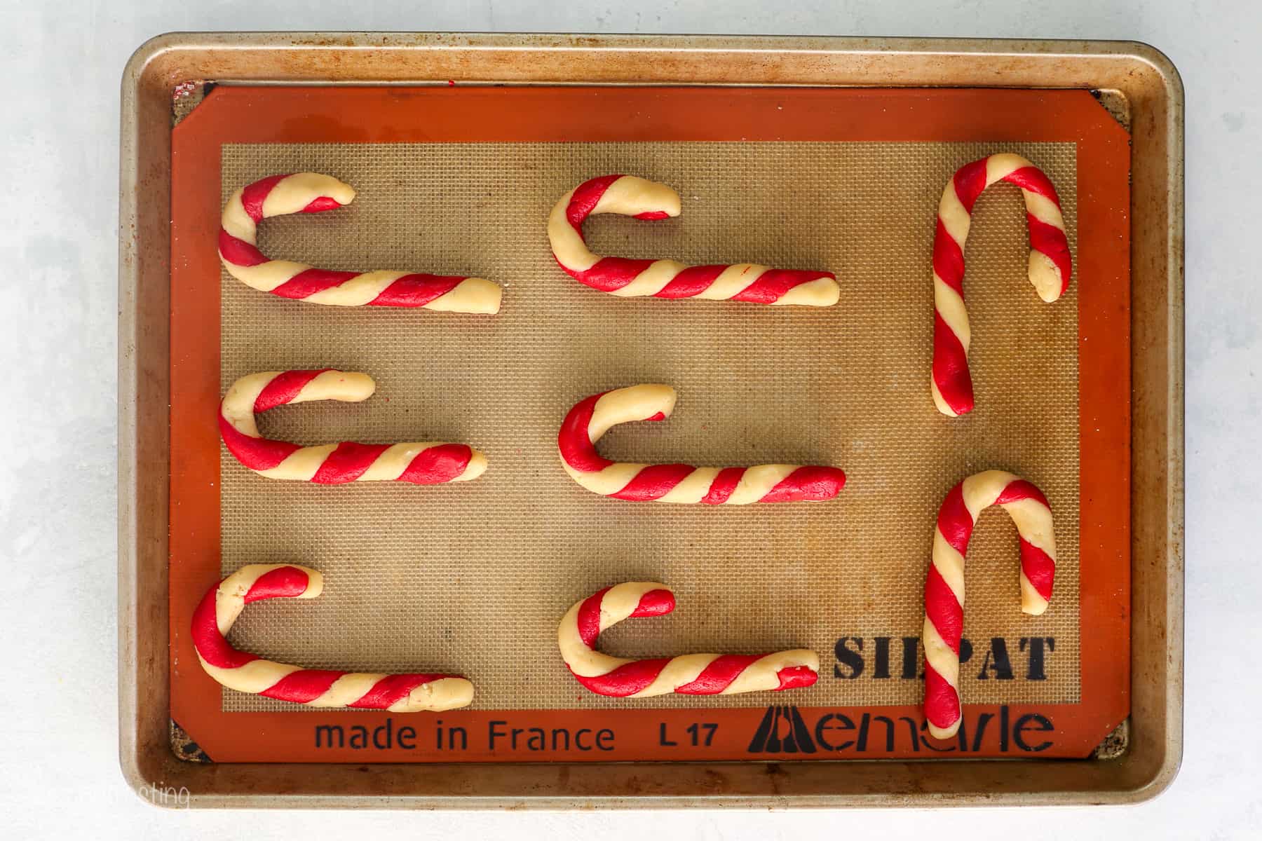 Overhead view of candy cane cookies on a silpat-lined baking sheet.