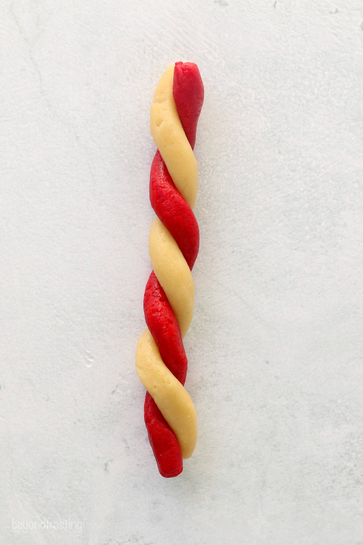 White and red sugar cookie dough ropes twisted together into a rope.