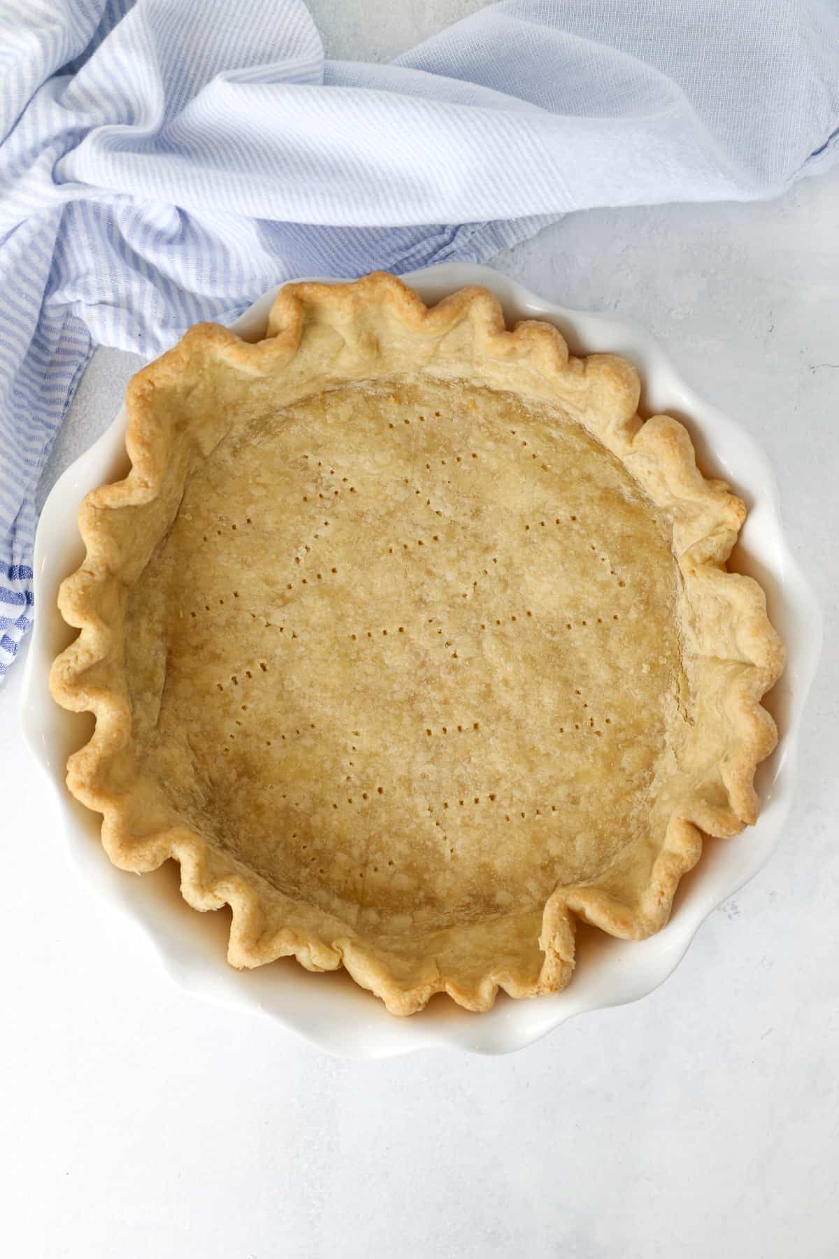 Overhead view of a fully baked pie crust in a pe plate.
