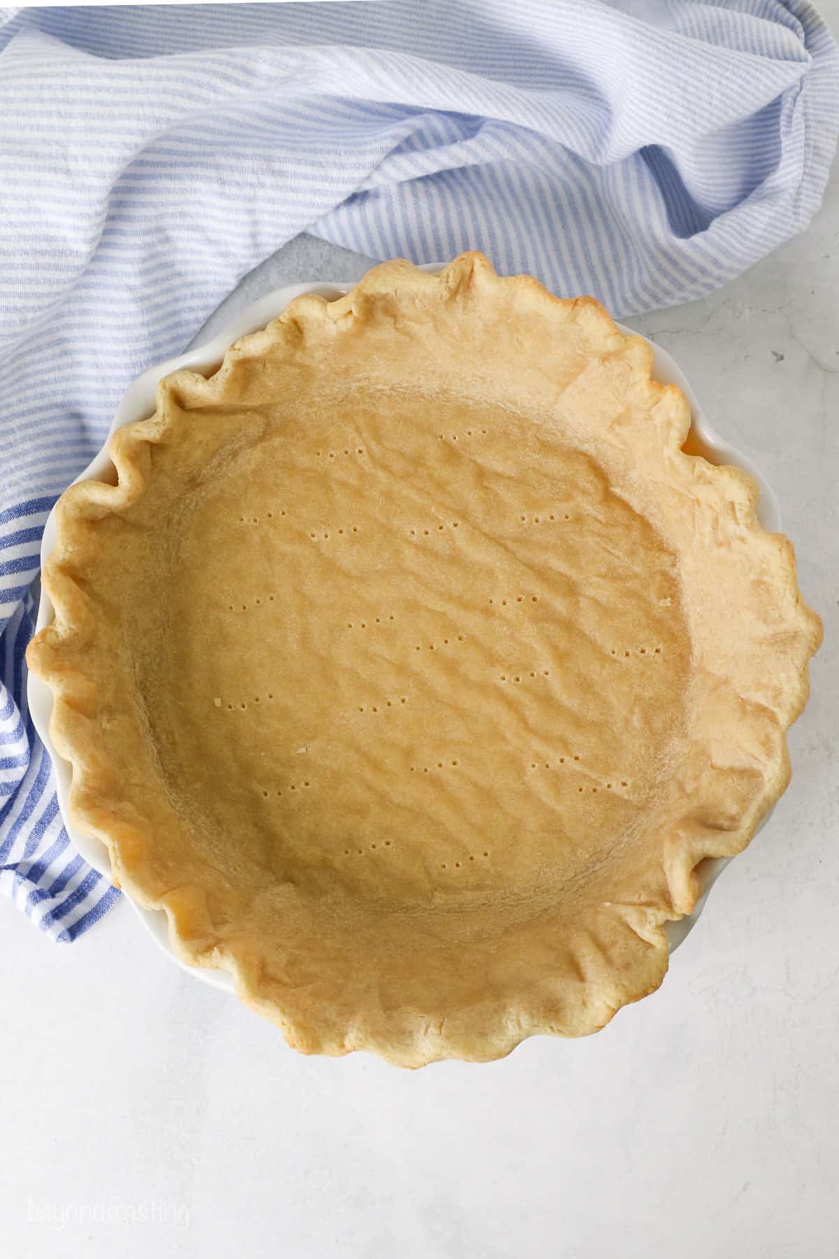 Overhead view of a partially baked pie crust in a pie plate after removing the pie weights.
