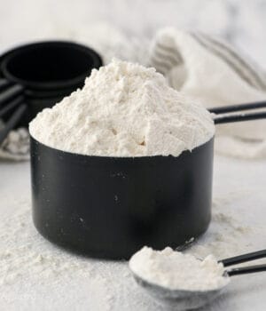 A heaping cup of flour in a black measuring cup