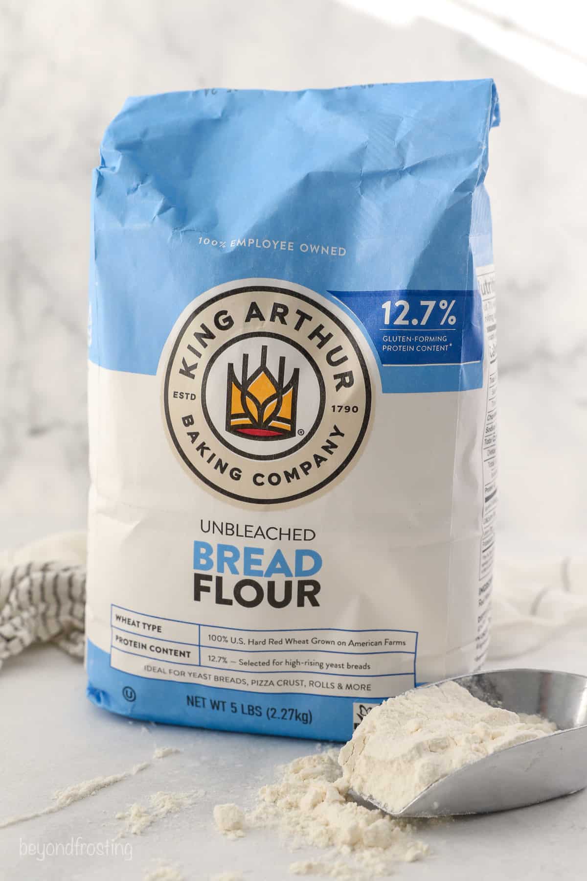 A bag of King Arthur Bread Flour with a scoop of flour next to it
