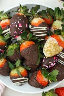An overhead view of a plate of decorated chocolate-covered strawberries