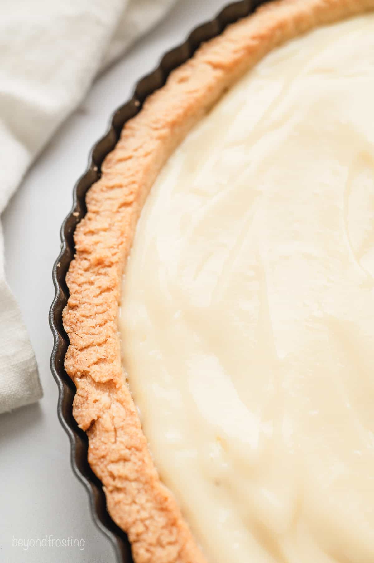 Overhead close up view of a tart shell filled with pastry cream.
