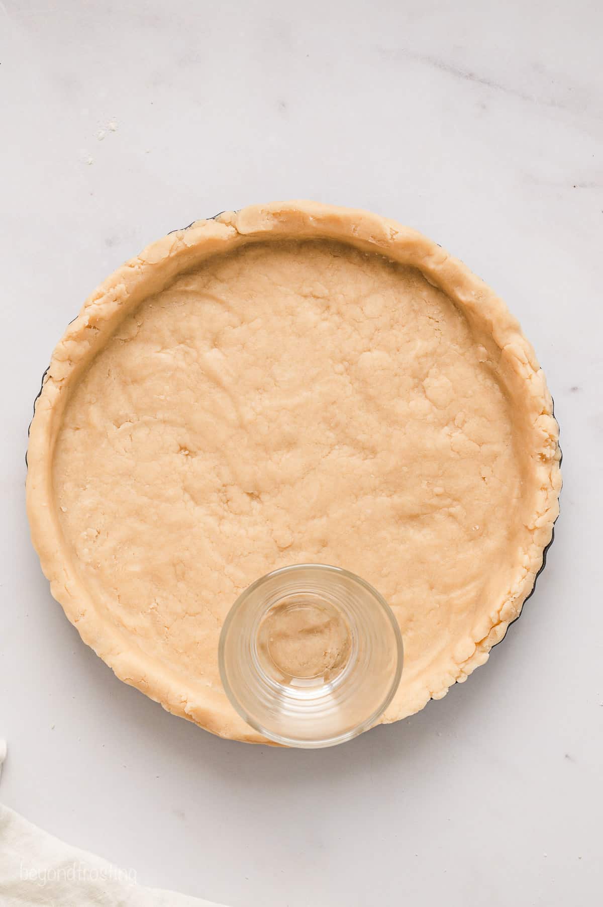 The bottom of a glass is used to press the pastry crust mixture into a pie plate.