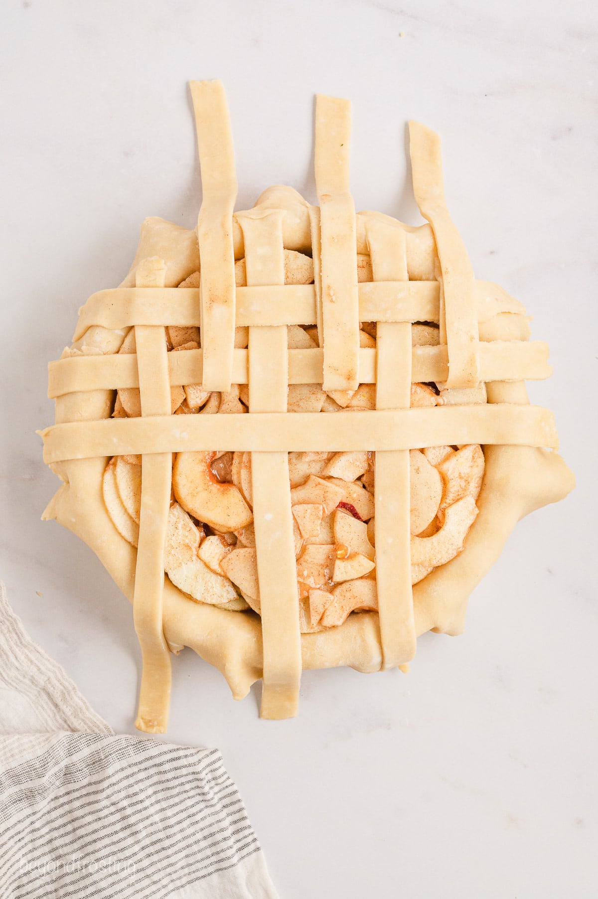 Partially woven lattice crust over a pie shell filled with pie filling.