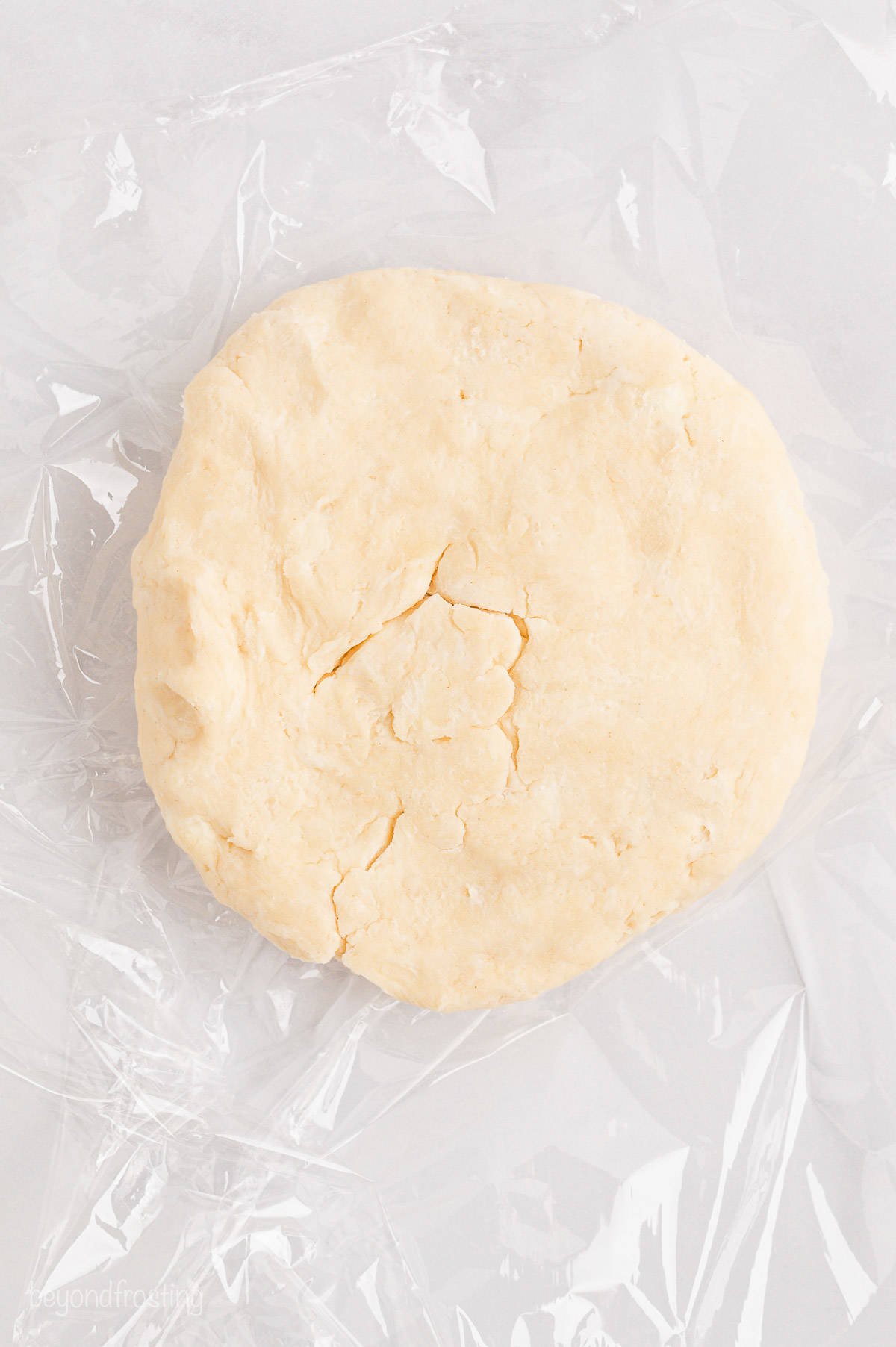 Pie dough shaped into a large disc on a floured surface.
