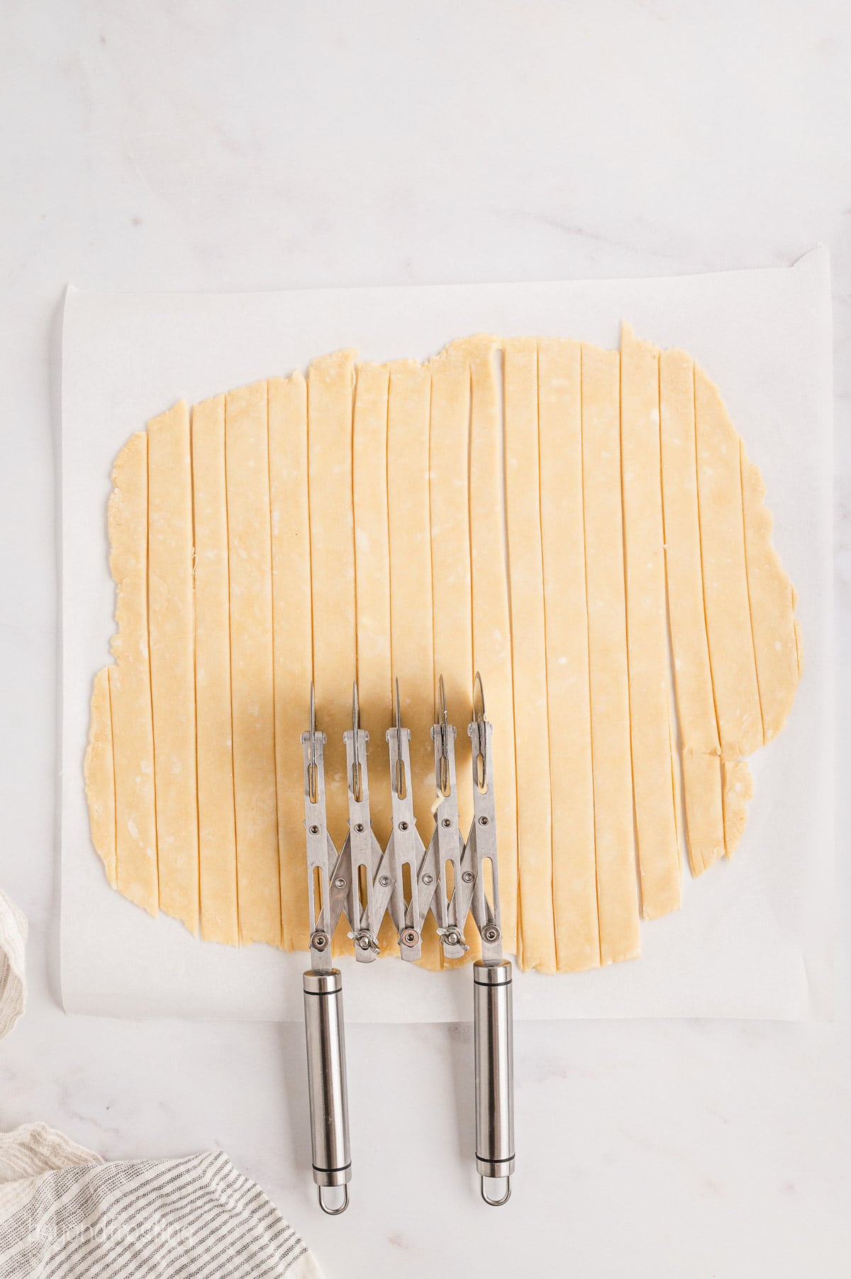 A pastry wheel cutter is used to cut pie crust into lattice strips.