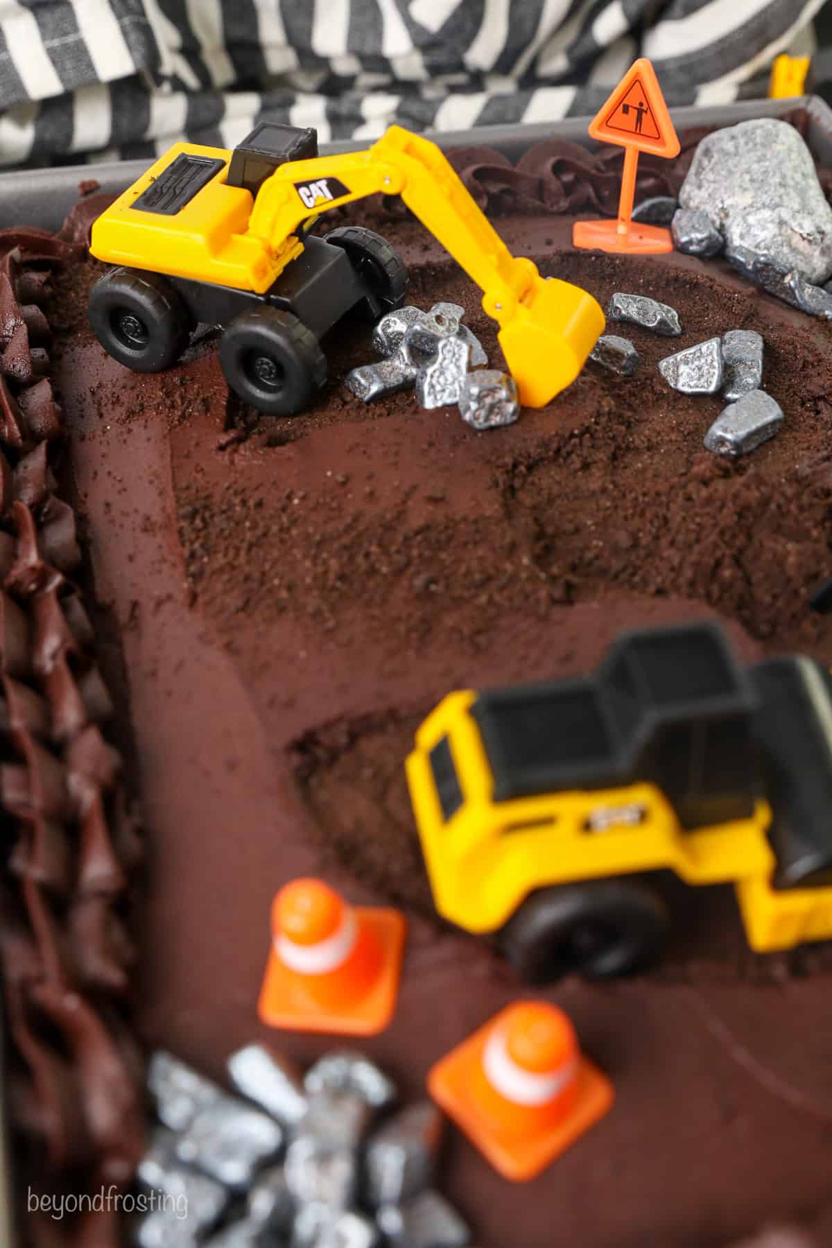 Close up of construction decorations on top of a frosted chocolate cake.