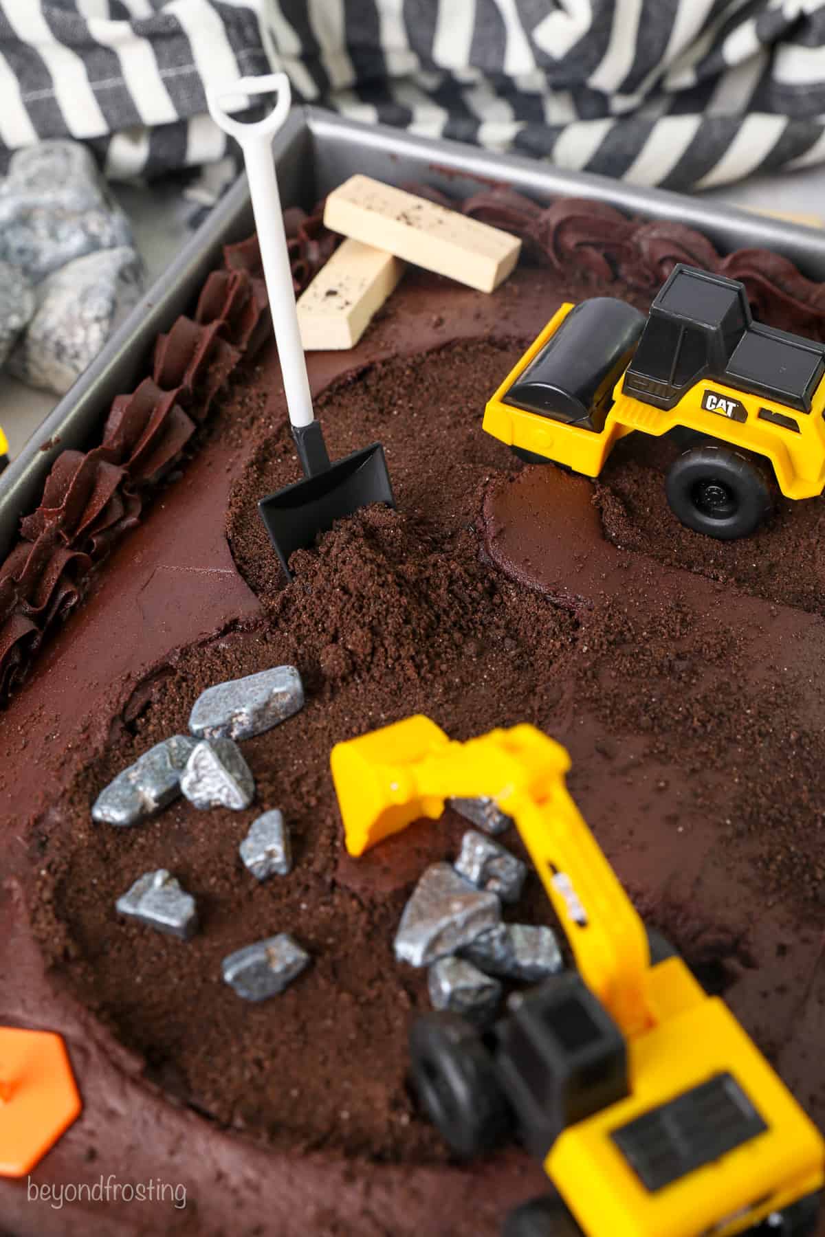 Close up of construction decorations on top of a frosted chocolate cake.
