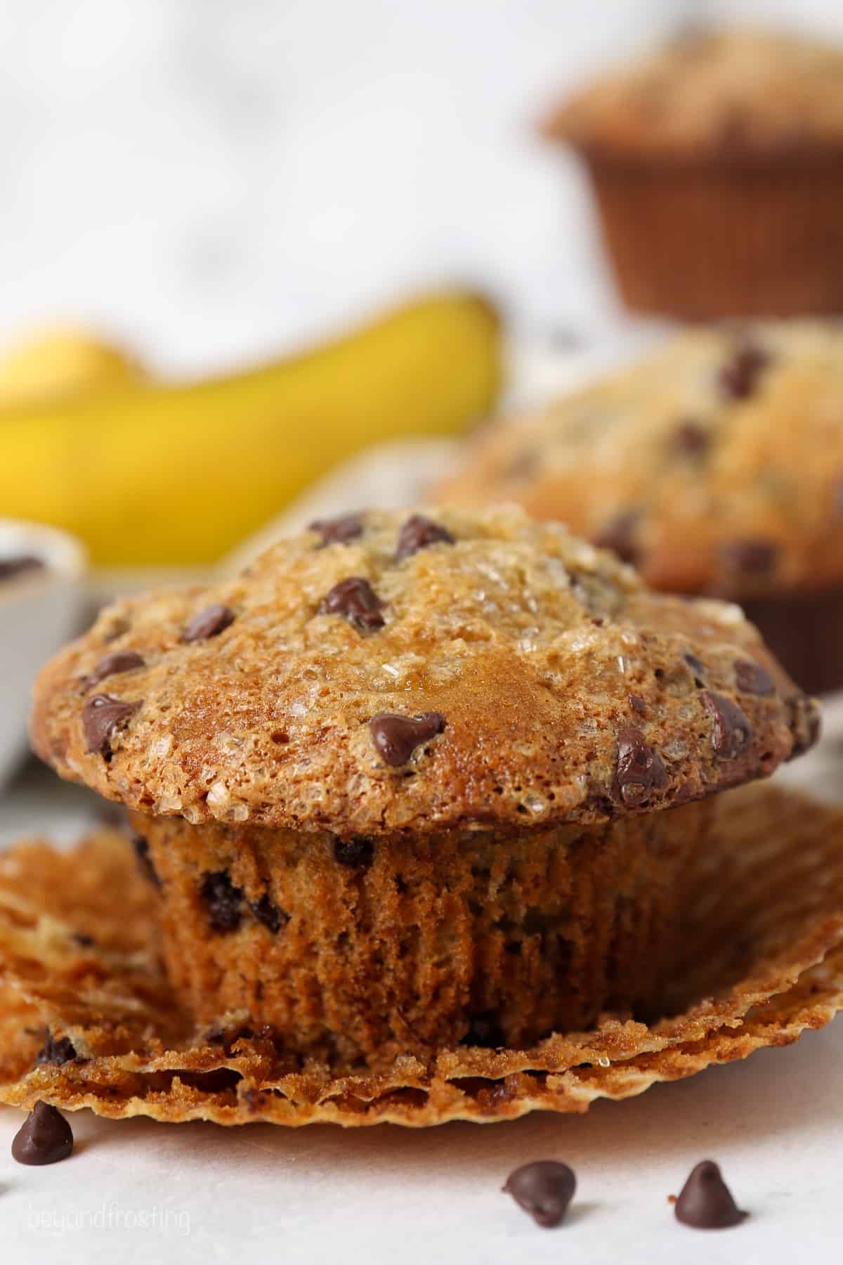 Close up of a partially unwrapped banana chocolate chip muffin.