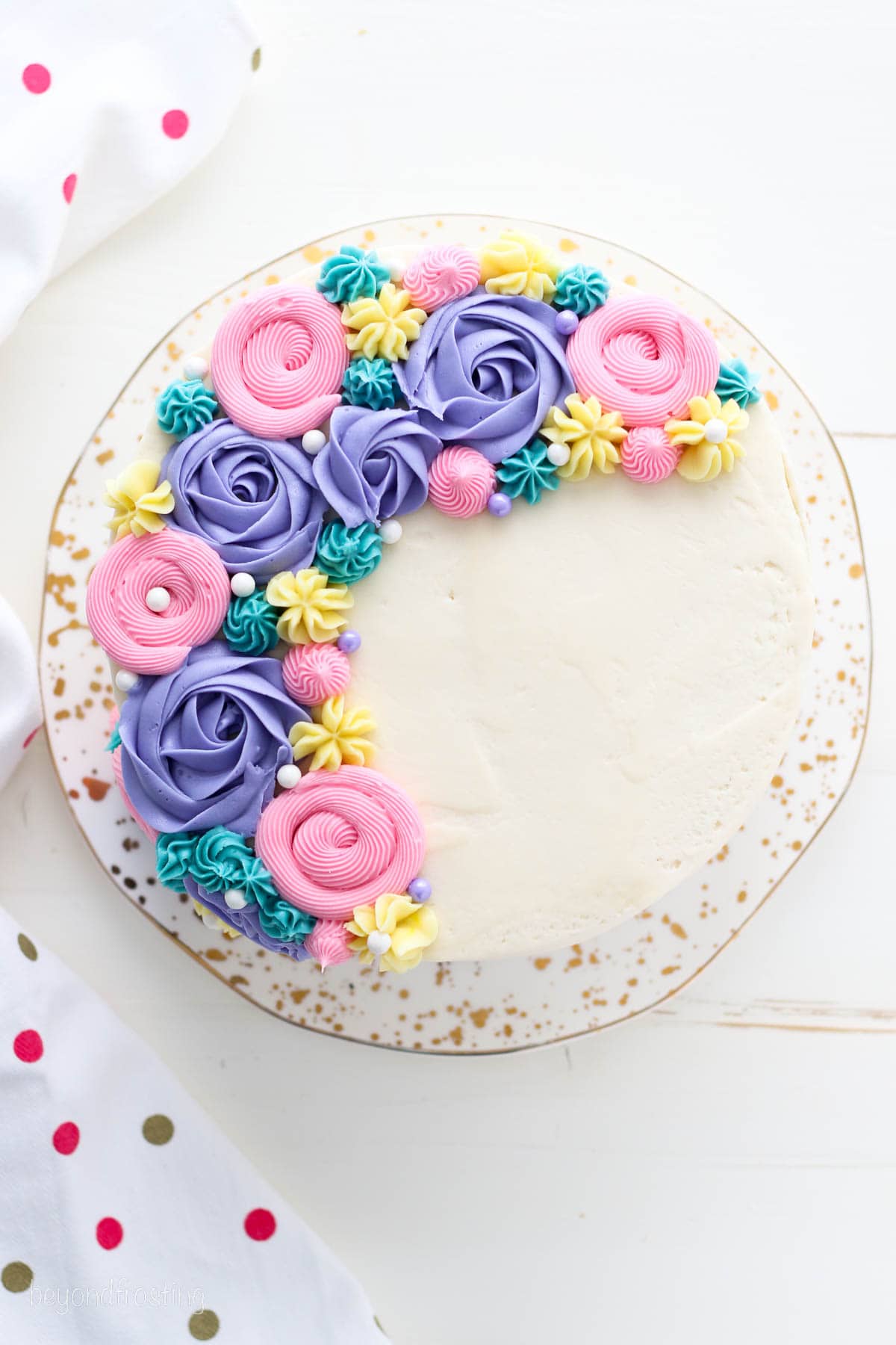 Overhead view of a buttercream flower cake decorated with pastel frosting rosettes and flowers.