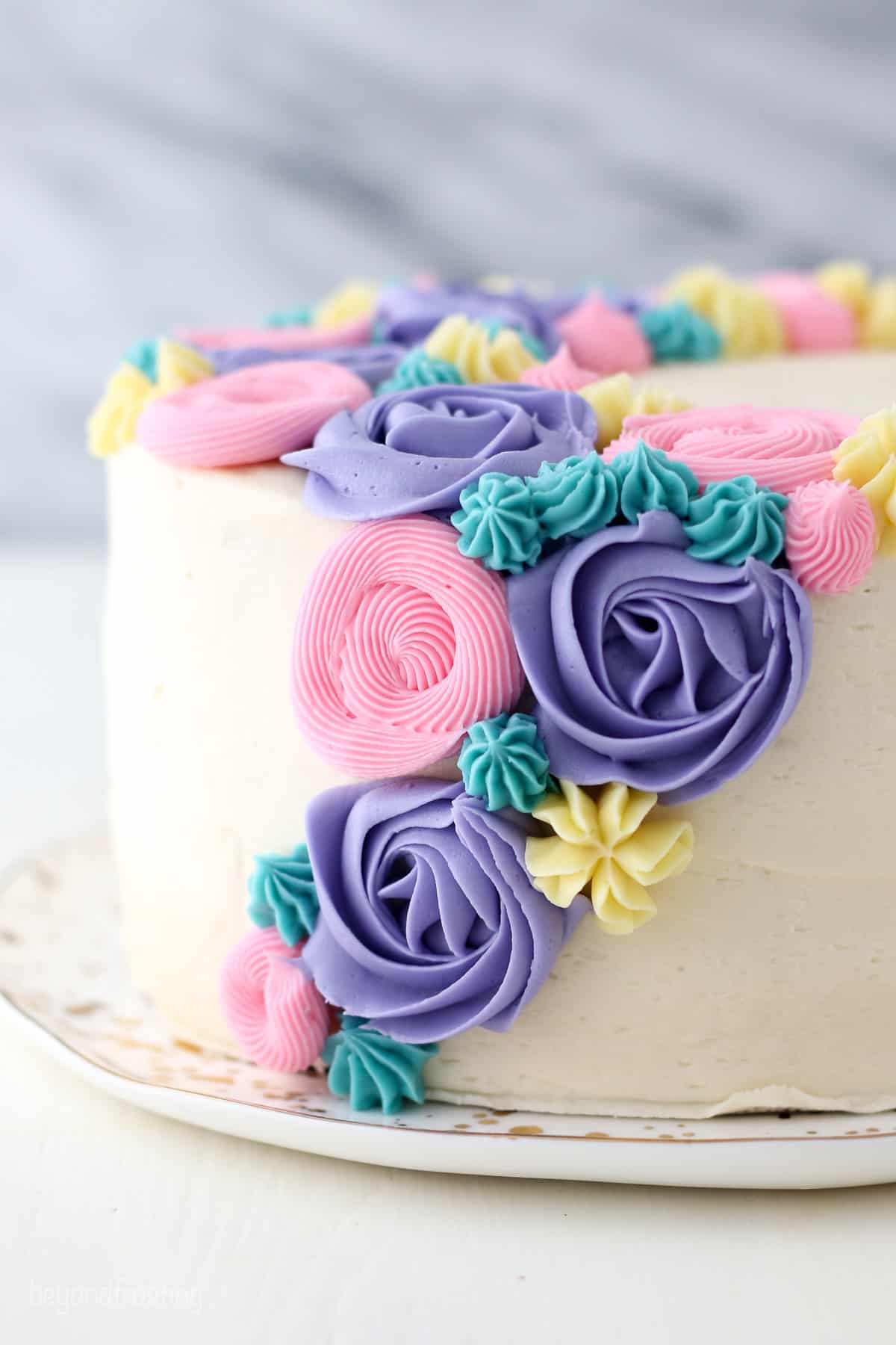 Side view of a buttercream flower cake decorated with pastel frosting rosettes and flowers.