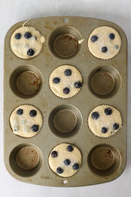overhead view of a cupcake pan with 6 of the cups filled with batter