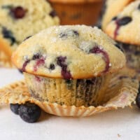 A close up of an unwrapped blueberry muffin with sanding sugar on top