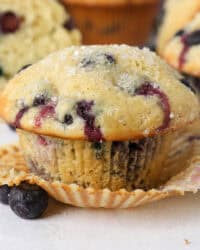 A close up of an unwrapped blueberry muffin with sanding sugar on top