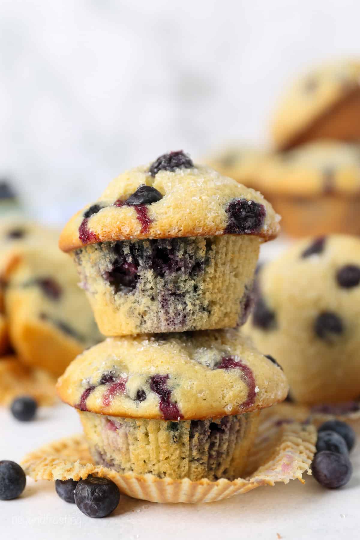 Two unwrapped blueberry muffins stacked o top of of another