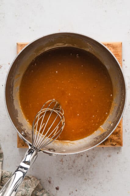 Sugar sauce in a saucepan with a whisk.