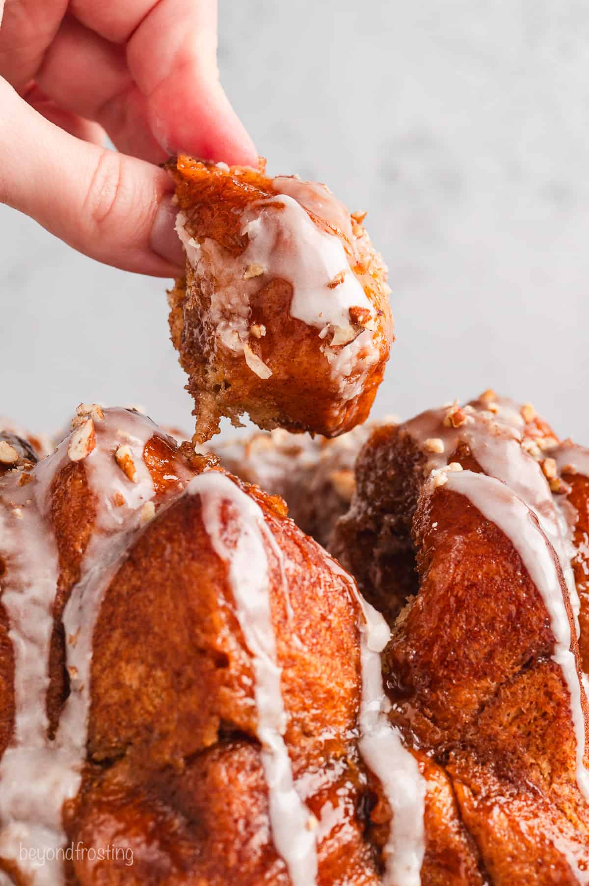 Close up of a hand pulling a piece of monkey bread free from the rest of the bread.