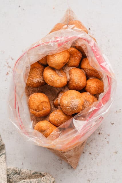Monkey bread dough balls coated in cinnamon sugar inside a large ziploc bag.