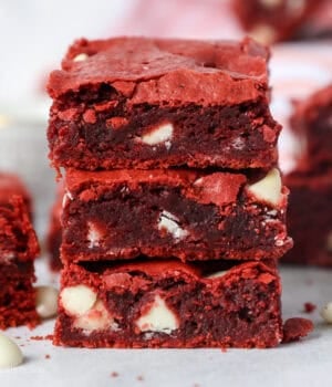 A stack of three red velvet brownies with more brownies in the background.