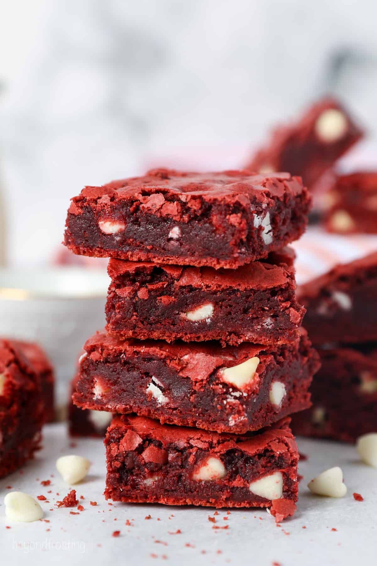 A stack of red velvet brownies with more brownies in the background.