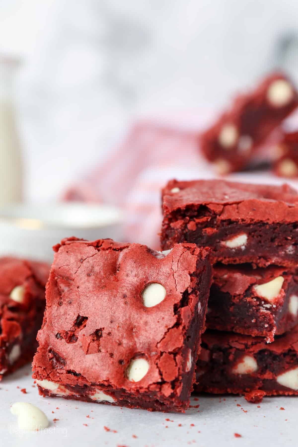 One red velvet brownie propped up against a stack of brownies.