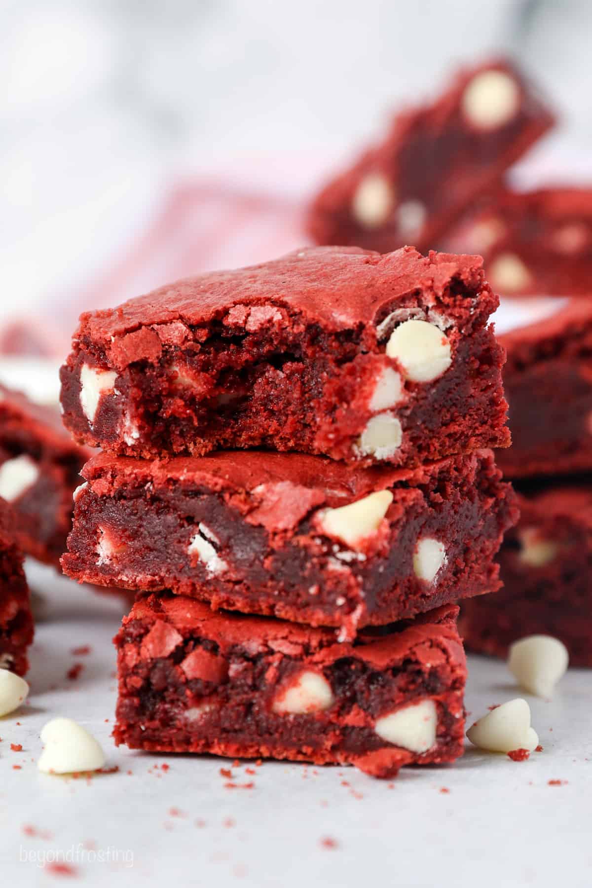 Close up of three red velvet brownies stacked on top of one another, with a bite missing from the top brownie.