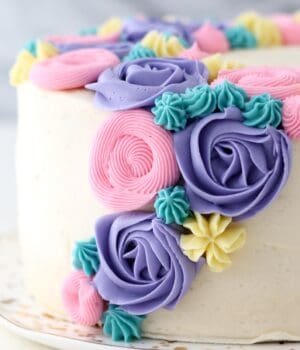 Close up of a buttercream flower cake decorated with pastel frosting rosettes and flowers.