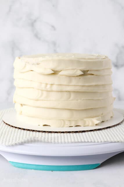 Banana layer cake covered with piped frosting on a cake stand.