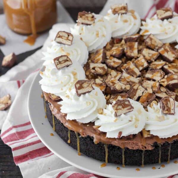 Snickers pie with whipped cream and chopped candy on top.