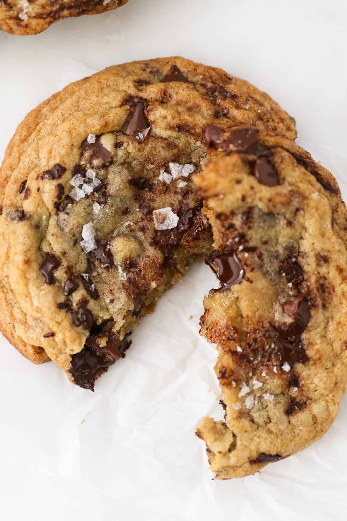 Overhead close up view of a giant chocolate chip cookie broken in half.
