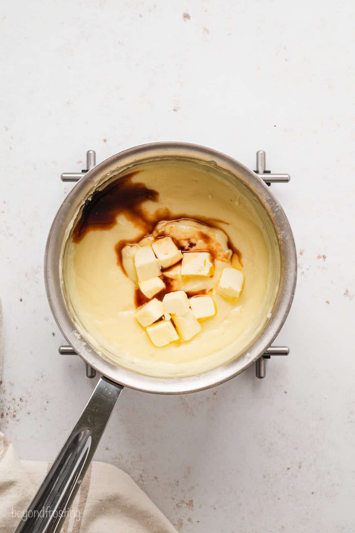 Vanilla extract and cubes of butter added to warm pudding in a saucepan.