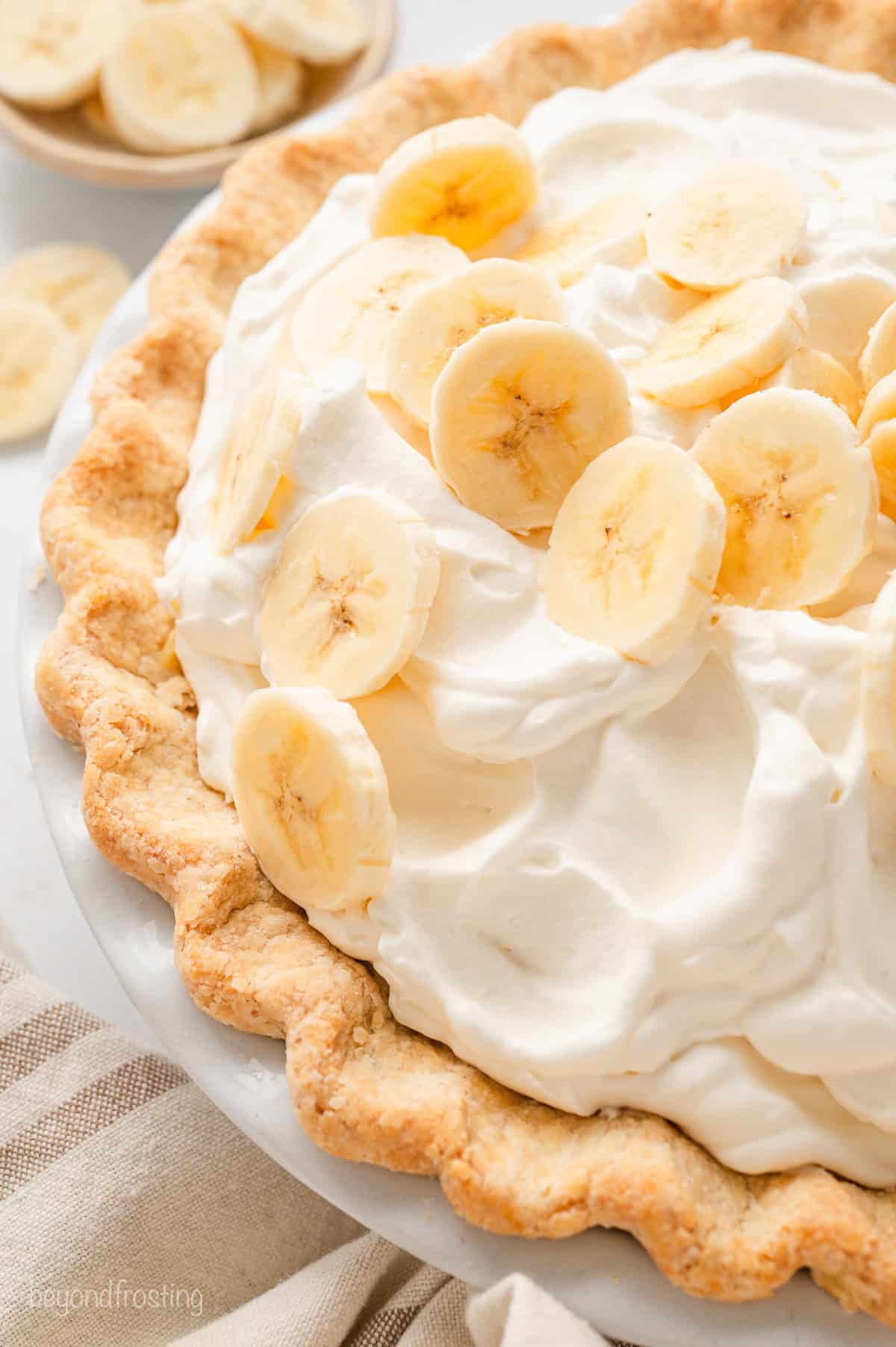 Overhead view of a whole banana cream pie garnished with banana slices.